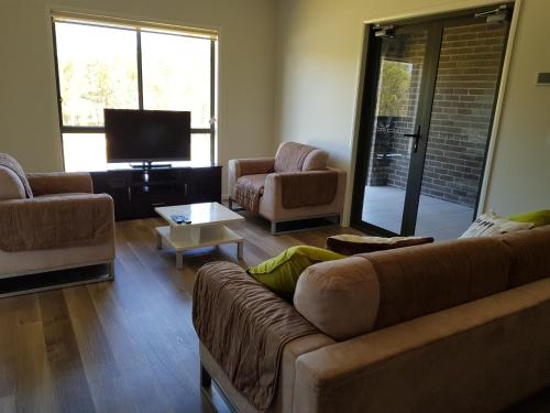 uma sala de estar com um sofá e cadeiras e uma televisão em Adwaga Lodge em Tamborine