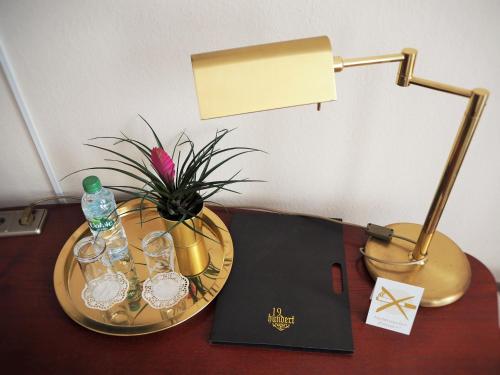 a table with a lamp and glasses and a book at Gala Hotel in Pforzheim