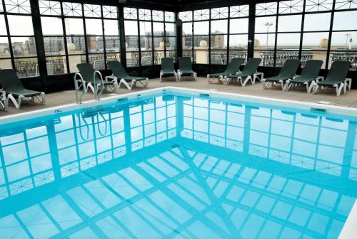 une grande piscine dans un immeuble avec des chaises dans l'établissement SOWELL RESIDENCES Le Port, à Trouville-sur-Mer