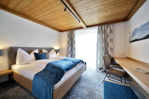 um quarto com uma cama grande e um cobertor azul em Frühstückspension Jagdhof em Obertilliach
