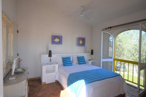 a bedroom with a bed with blue pillows and a balcony at V2 Aldeia Do Golf- Piscina, Familiar, Aconchegante in Vilamoura