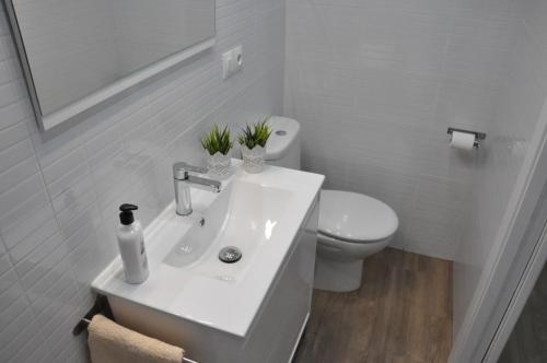 La salle de bains blanche est pourvue d'un lavabo et de toilettes. dans l'établissement La Casita De Angela, à Frigiliana
