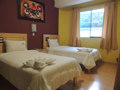 a hotel room with two beds and a window at Samay Wasi Hotel Chalhuanca in Chalhuanca