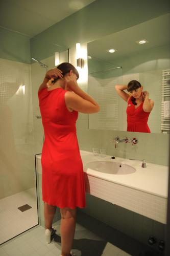 a woman in a red dress standing in front of a bathroom mirror at Villa Vanilla in Kędzierzyn-Koźle