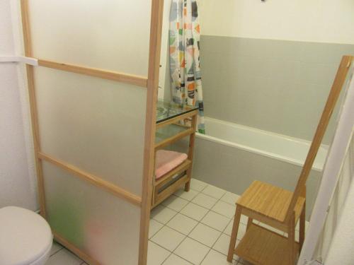 une salle de bain avec une douche et des toilettes et un tabouret dans l'établissement Appartement Grand Calypso, à Frontignan