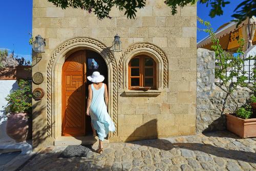 a woman in a hat standing in front of a door at Melenos Art Boutique Hotel in Líndos