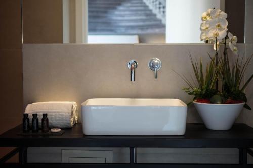 a bathroom sink on a black counter with flowers at Family Affair Luxury Rooms&Suites in Palermo