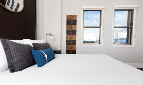 a bedroom with a white bed with two windows at Harbor Court Hotel in San Francisco