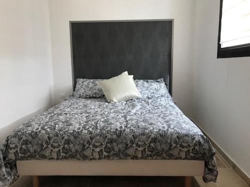 uma cama com uma cabeceira preta e uma almofada branca em Maison PROVENCALE em Arles