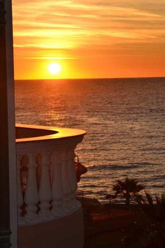 a sunset on the beach with the ocean in the background at Hotel Piccolo Lido in Bordighera