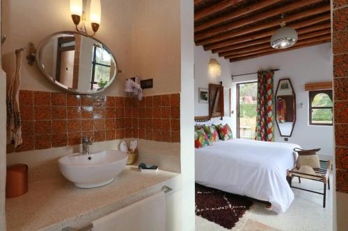 a bedroom with a bed and a sink and a mirror at Domaine Malika - Adults Only in Ouirgane