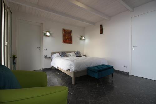 1 dormitorio con 1 cama blanca y 1 sofá verde en Casa Adriana, en Cefalú