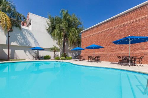 a large swimming pool with blue umbrellas and tables at Wyndham Garden Monterrey Norte in Monterrey