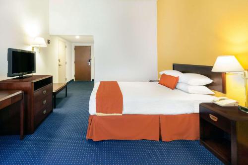 a hotel room with a bed and a flat screen tv at Wyndham Garden Monterrey Norte in Monterrey