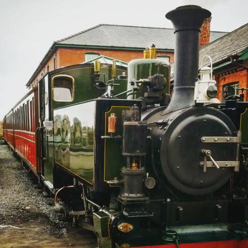a black train is parked next to a building at The Firecat Country House Guesthouse in Mallwyd