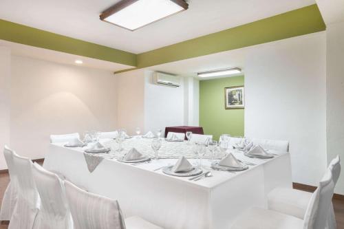 a dining room with a white table and white chairs at Wyndham Garden Obregon in Ciudad Obregón