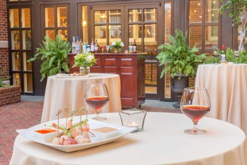 a table with two wine glasses and a plate of food at The George Washington - A Wyndham Grand Hotel in Winchester