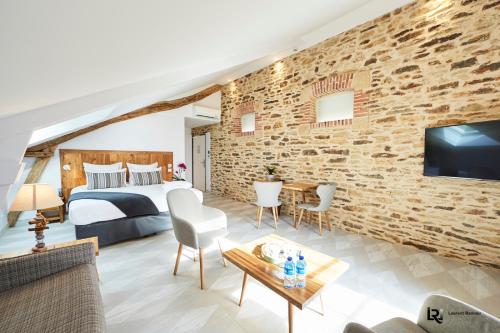 een slaapkamer met een bed en een bakstenen muur bij Le Manoir de Kerbot in Sarzeau