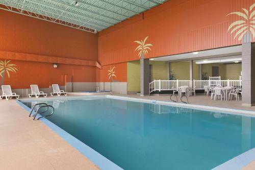 a swimming pool with chairs and tables in it at Travelodge by Wyndham Edmundston in Edmundston