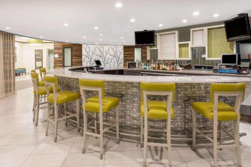 a bar with yellow stools in a hotel lobby at Wyndham Garden Summerville in Summerville