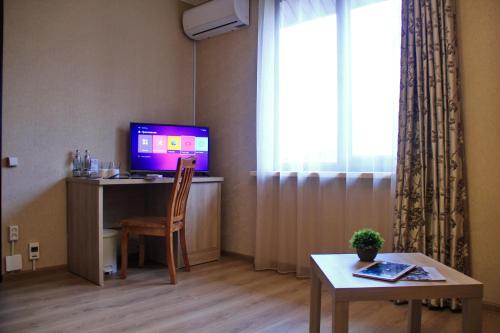 a living room with a desk with a television and a table at Lavitor hotel in Bishkek