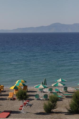 a group of chairs and umbrellas on a beach at Pylea Beach Hotel in Ialyssos