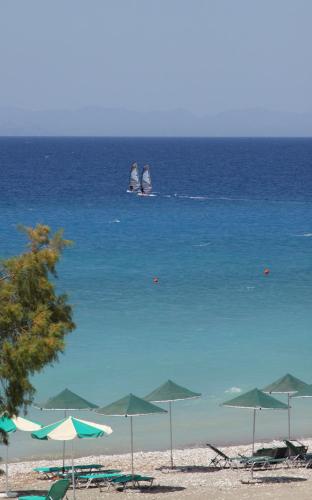 a group of umbrellas on a beach with the ocean at Pylea Beach Hotel in Ialyssos