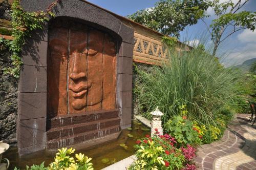 a wooden door with a face on it in a garden at La Buena Vibra Retreat and Spa Hotel in Tepoztlán
