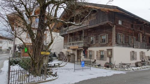 an old wooden house with a tree in the snow at Hoamatl in Ebbs