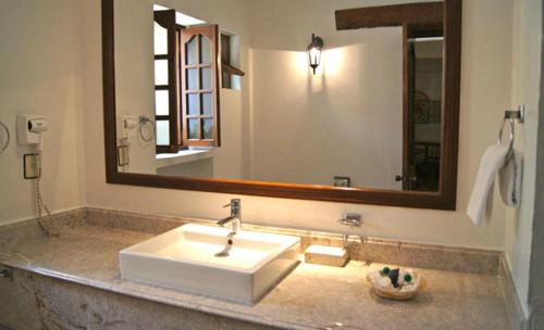 a bathroom with a sink and a large mirror at Suites Colibri in Oaxaca City