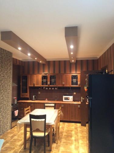a kitchen with wooden cabinets and a table and chairs at Bachos Apartment in Tbilisi City