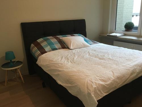 een groot bed in een slaapkamer met een tafel en een raam bij Appartement in hartje Gent in Gent