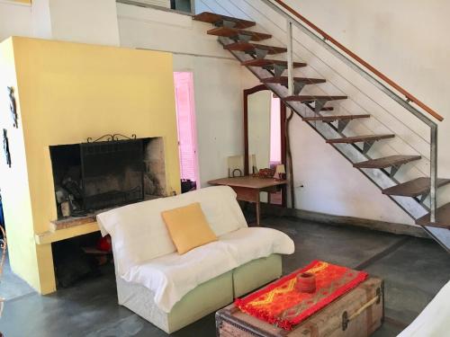 a living room with a white chair and a staircase at Casa en colonia para 7 personas in Colonia del Sacramento