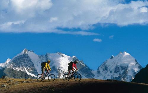 two people riding bikes on a hill in front of a mountain at Résidence "Les Crêtes" in Torgon
