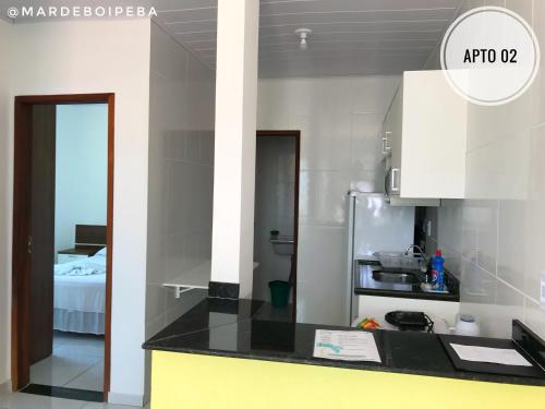 a kitchen with white cabinets and a black counter top at Mar de Boipeba in Ilha de Boipeba