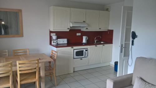 uma cozinha com armários brancos e uma mesa com um micro-ondas em appartement bord de mer em Fouesnant