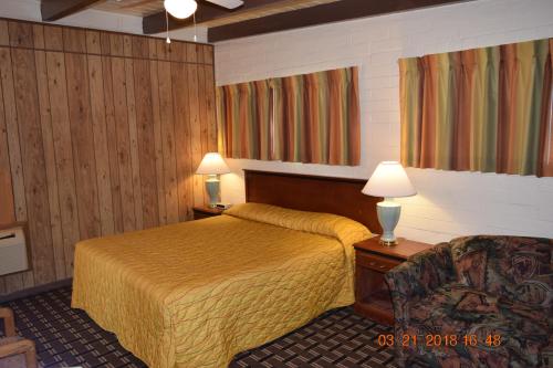a hotel room with a bed and a chair at Stanlunds Inn and Suites in Borrego Springs