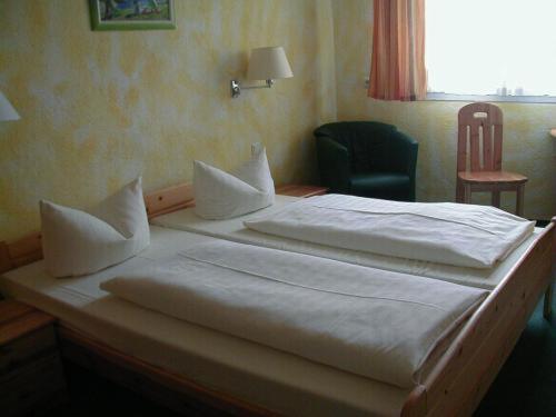 two beds in a bedroom with a chair and a window at Hotel Goldener Karpfen in Aschaffenburg