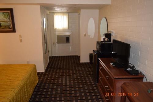 a hotel room with a bed and a flat screen tv at Stanlunds Inn and Suites in Borrego Springs