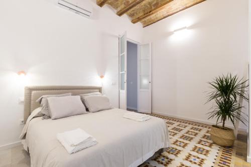 a white bedroom with a large bed and a potted plant at Casa Nolla in Valencia