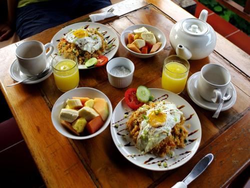 a wooden table with plates of food and cups of orange juice at Bali Bhuana Villas in Amed