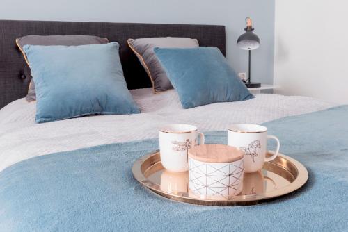 a tray with two coffee mugs on a bed at "Apartament na Kazimierzu" in Krakow