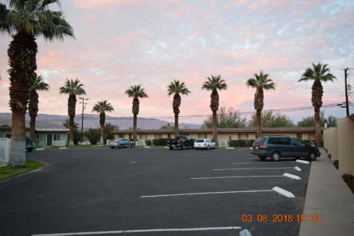 a parking lot with palm trees in front of a motel at Stanlunds Inn and Suites in Borrego Springs