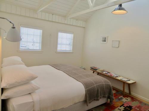 a bedroom with a bed and two windows at The Oyster Inn in Oneroa