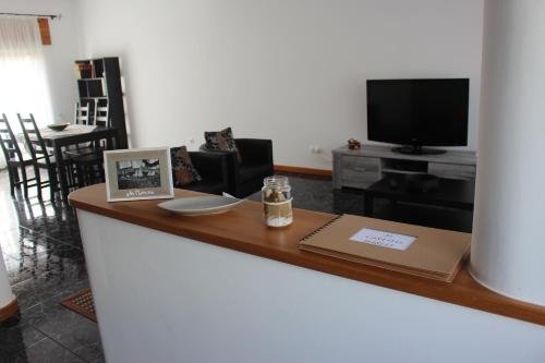 a living room with a counter with a television and a table at Casa das Marias in Horta