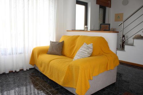 a yellow blanket on a couch in a room at Casa das Marias in Horta