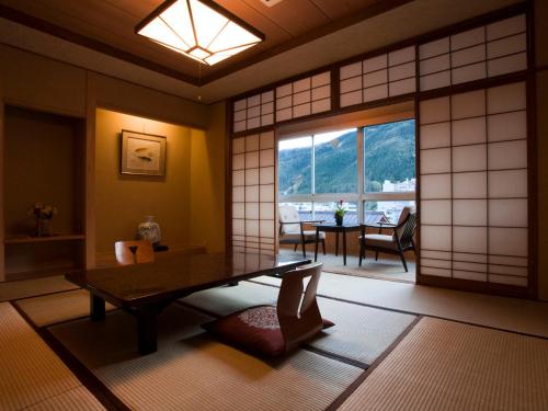 a japanese room with a table and a window at Gero Onsen Fugaku in Gero
