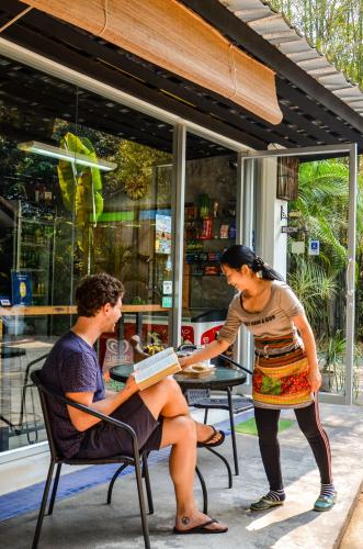 a woman standing next to a man sitting at a table at Rice Barn And Rooms in Hang Dong