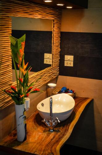 a bathroom with a sink and a vase with flowers at Rice Barn And Rooms in Hang Dong
