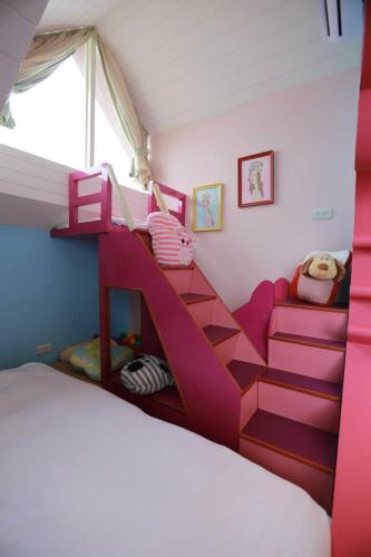 a bedroom with a pink bunk bed and stairs at Travel Light in Jiaoxi